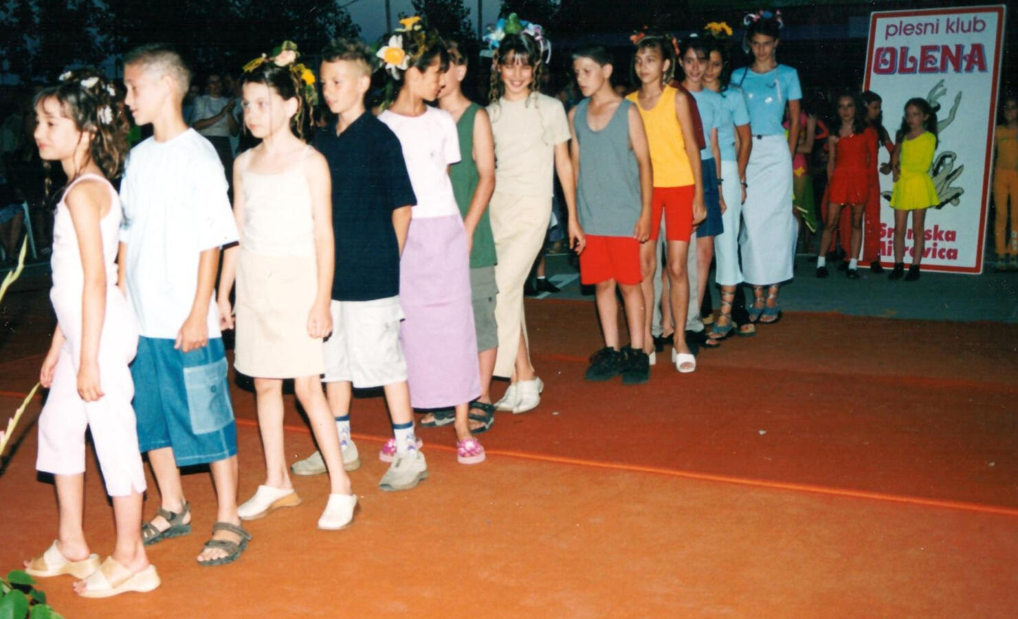 Dečja modna revija Predstavljanje kolekcije modne firme iz Sremske Mitrovice, sa punđom ukrašenom cvećem. Prvi koraci na sceni, spoj igre, umetnosti i osmeha.led